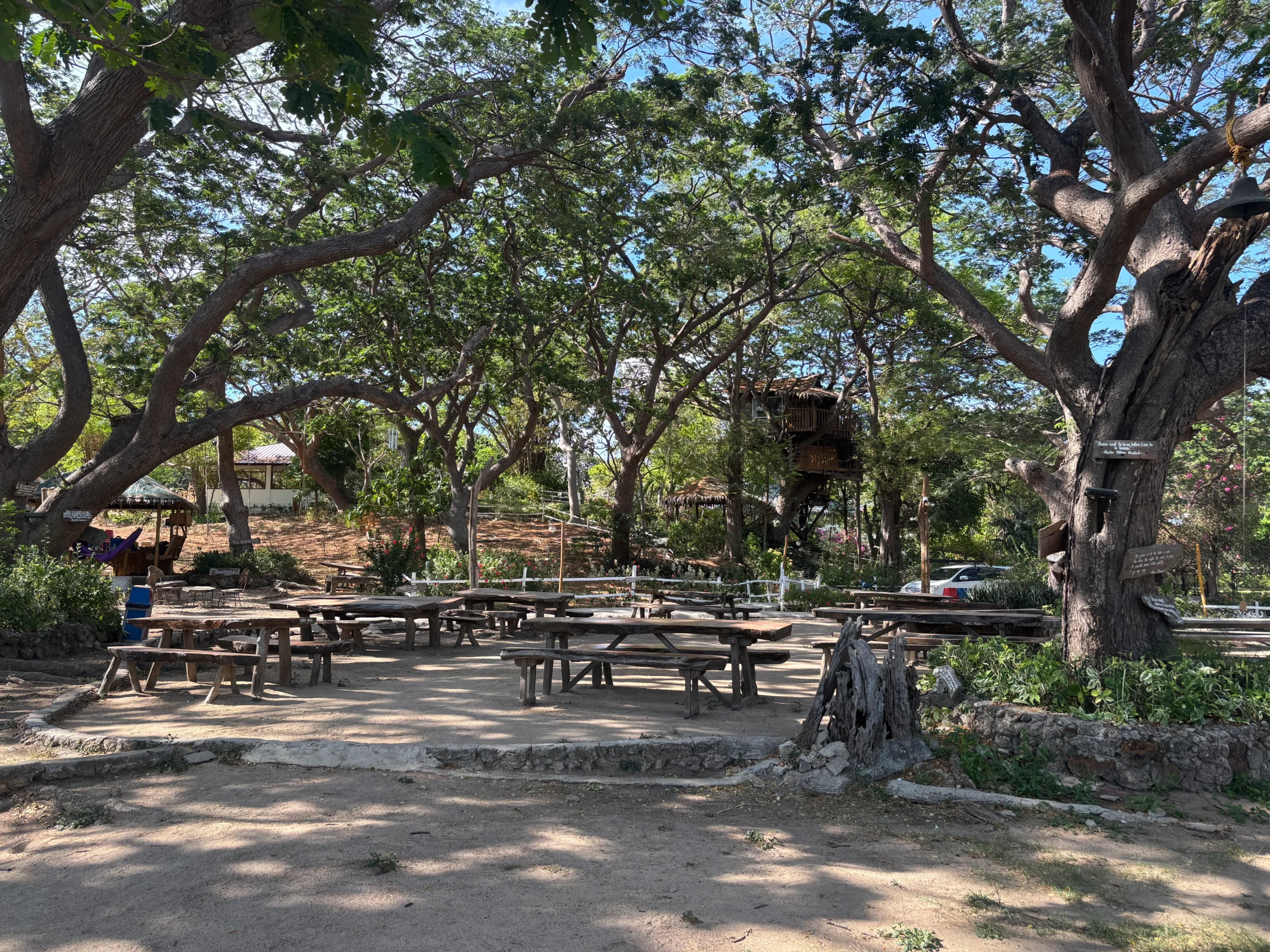 Open-air tables beneath trees at Stilts Calatagan