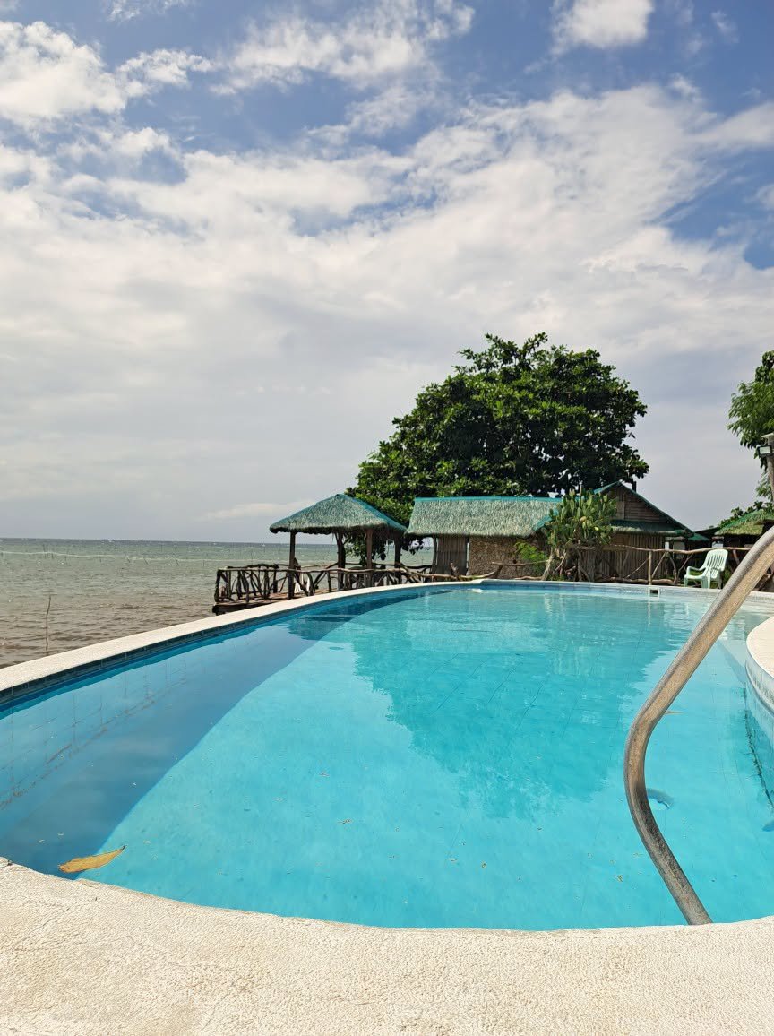 Swimming pool overlooking the sea and cottages at Ronco Beach Resort