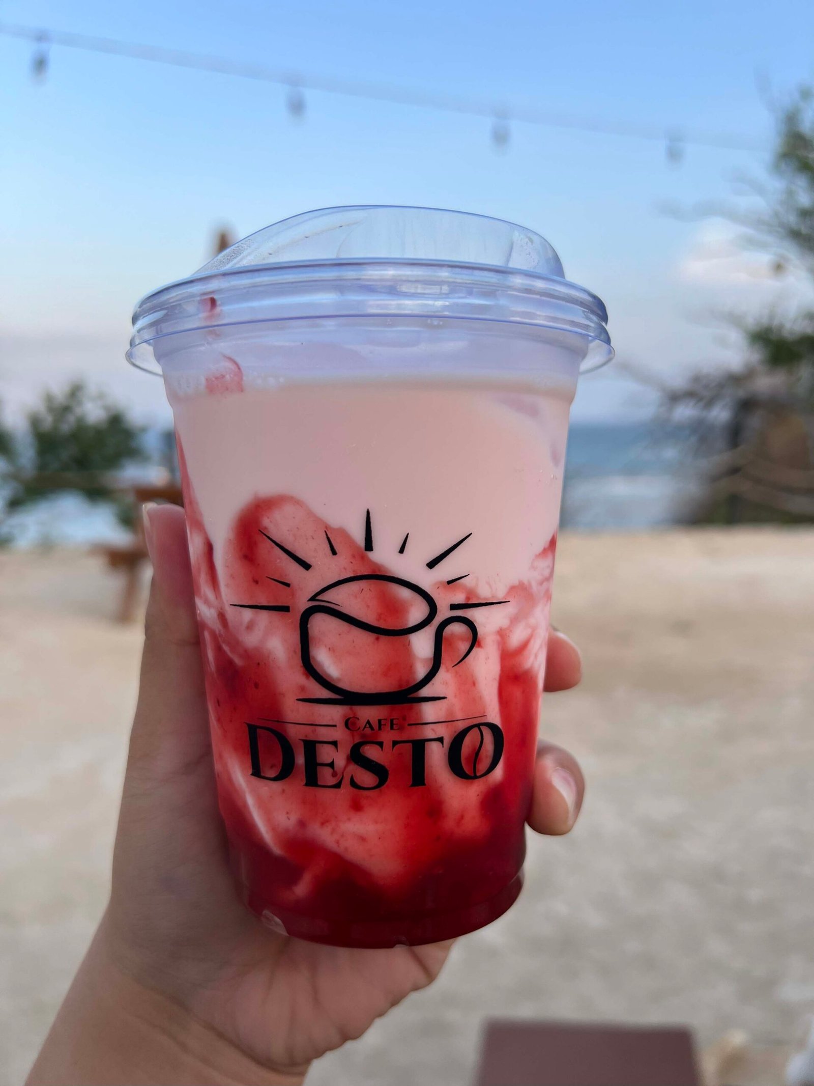 Pink iced drink in a Café Desto branded cup