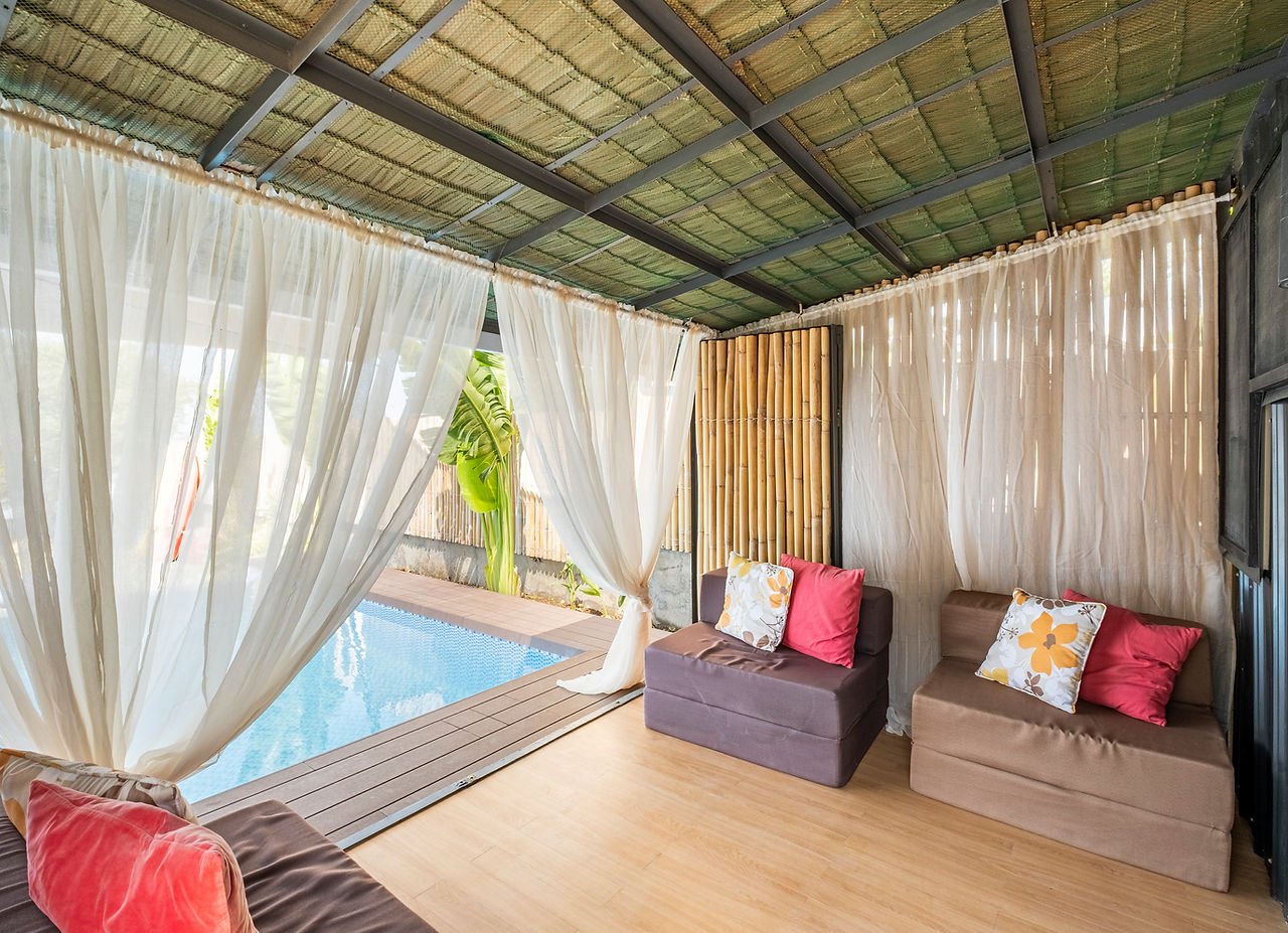 Curtained lounge beside the pool at Tirta Cottages