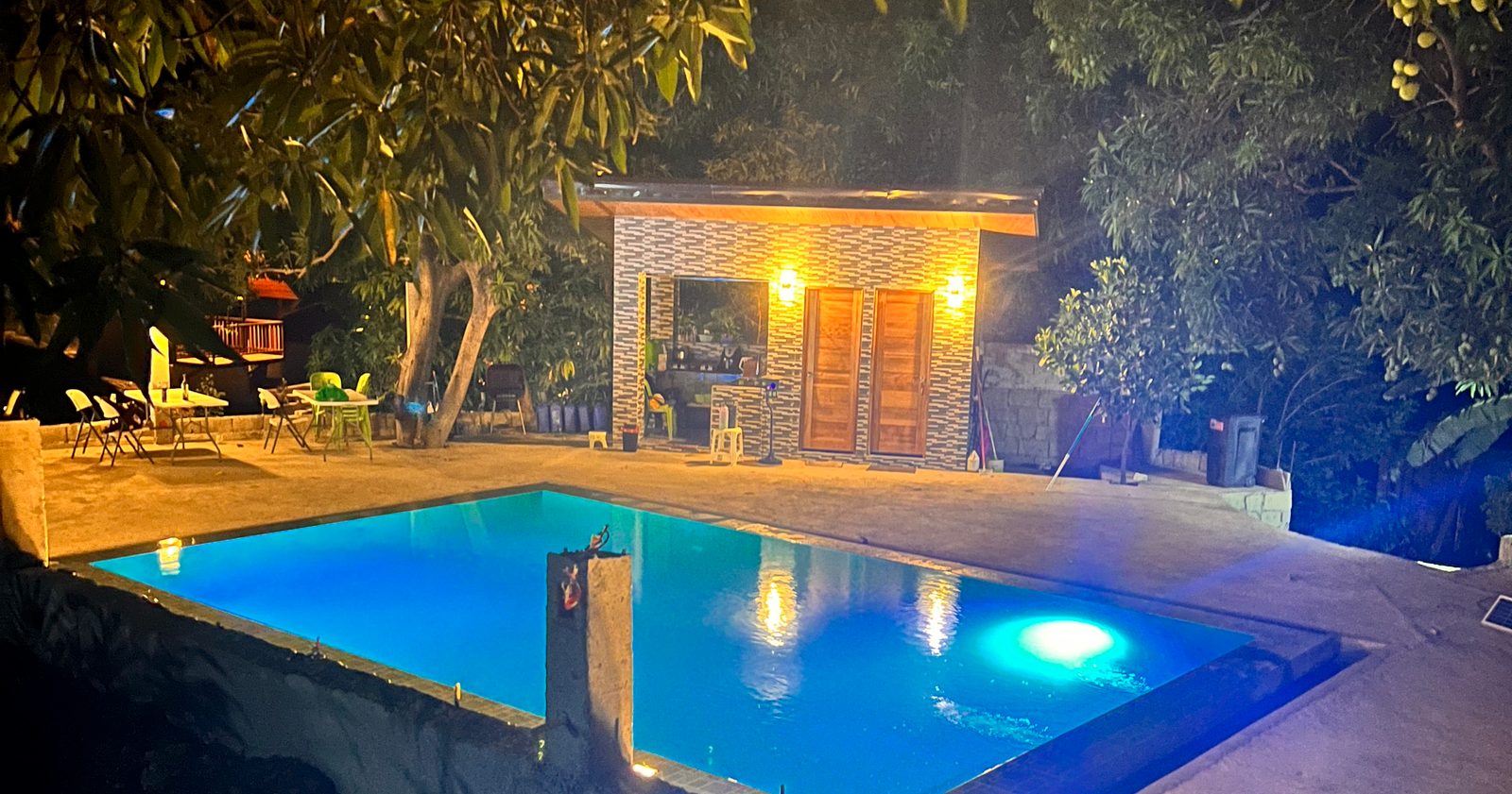 Swimming pool and poolside building at Unwind Calatagan Leisure Farm at night